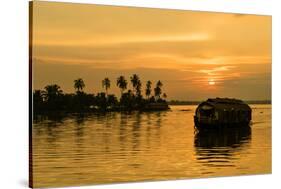 A traditional houseboat moves past the setting sun on the Kerala Backwaters, Kerala, India, Asia-Logan Brown-Stretched Canvas