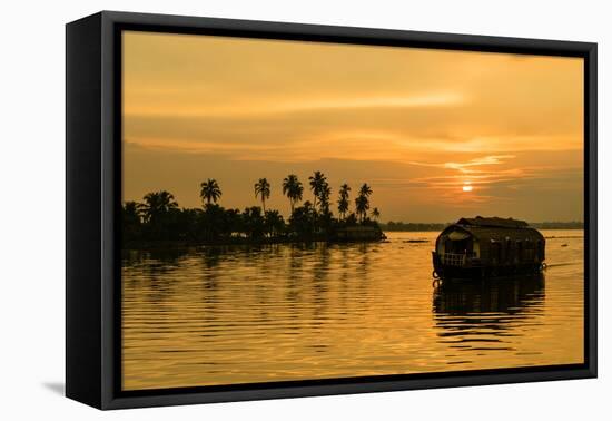 A traditional houseboat moves past the setting sun on the Kerala Backwaters, Kerala, India, Asia-Logan Brown-Framed Stretched Canvas