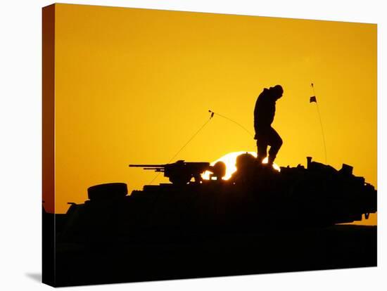 A U.S. Soldier Walks Atop His Armored Vehicle at Sunset-null-Stretched Canvas