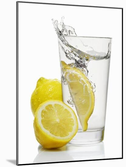 A Wedge of Lemon Falling into a Glass of Water-Kröger & Gross-Mounted Photographic Print