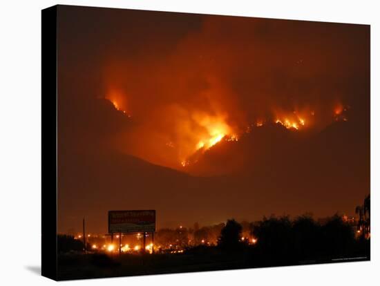 A Wildfire Can be Seen Raging in the Hills Over the Town of St. Ignatius, Montana-null-Stretched Canvas