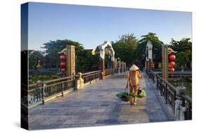 A woman carrying baskets on a yoke over the Lantern Bridge in Hoi An, Quang Nam, Vietnam, Indochina-Alex Robinson-Stretched Canvas