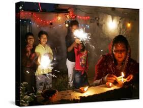 A Woman Lights Earthen Lamps as Children Ignite Firecrackers in New Delhi-Manish Swarup-Stretched Canvas