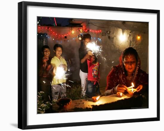 A Woman Lights Earthen Lamps as Children Ignite Firecrackers in New Delhi-Manish Swarup-Framed Photographic Print