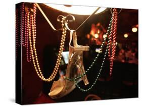 A Woman's High Heeled Shoe Hangs with Some Mardi Gras Beads-null-Stretched Canvas