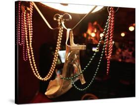 A Woman's High Heeled Shoe Hangs with Some Mardi Gras Beads-null-Stretched Canvas