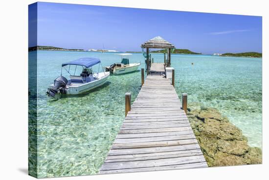 A Wood Pier Leads to Moored Boats and Clear Tropical Waters Near Staniel Cay, Exuma, Bahamas-James White-Stretched Canvas