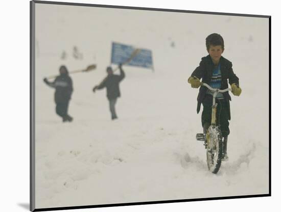 A Young Afghan Boy Rides His Bicycle on a Snow Covered Street-null-Mounted Photographic Print