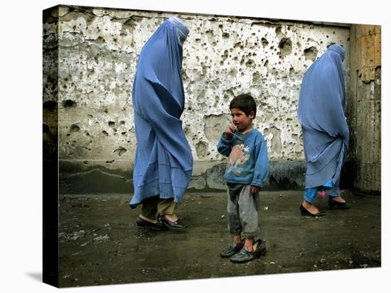 A Young Afghan Refugee Boy Stands in a Pair of Adult's Shoes-null-Stretched Canvas