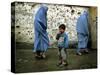 A Young Afghan Refugee Boy Stands in a Pair of Adult's Shoes-null-Stretched Canvas