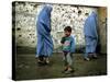 A Young Afghan Refugee Boy Stands in a Pair of Adult's Shoes-null-Stretched Canvas