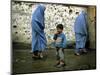 A Young Afghan Refugee Boy Stands in a Pair of Adult's Shoes-null-Mounted Photographic Print