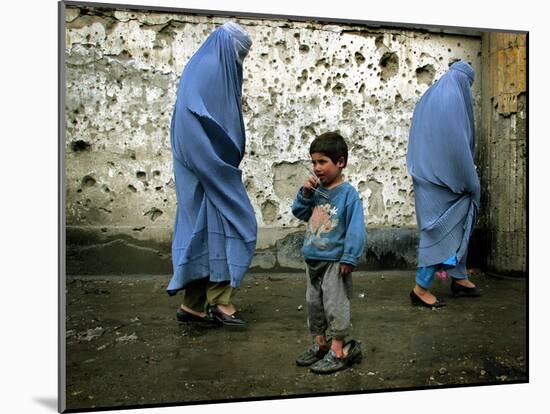 A Young Afghan Refugee Boy Stands in a Pair of Adult's Shoes-null-Mounted Photographic Print