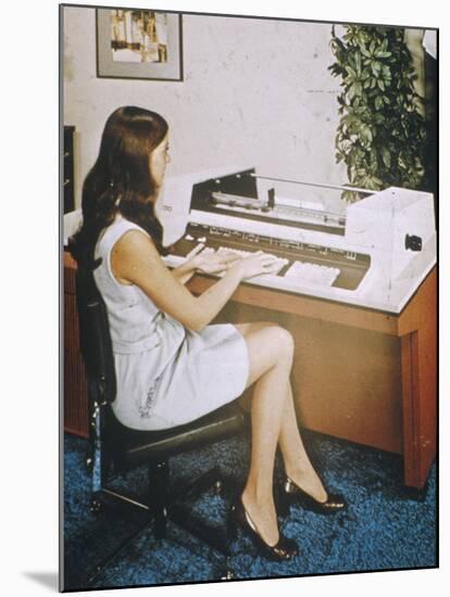 A Young Woman Office Worker Using What Now Looks Like a Rather Cumbersome Computer-null-Mounted Photographic Print