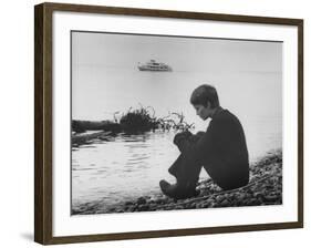 Actress Mia Farrow Pensively Sitting on Rocky Shore of Lake Geneva as Passenger Boat Passes By-Bill Eppridge-Framed Premium Photographic Print