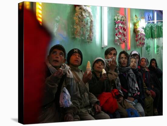 Afghan Boys Watch a Movie on a Television, Unseen, as They Eat Ice Cream at an Ice Cream Shop-Rodrigo Abd-Stretched Canvas