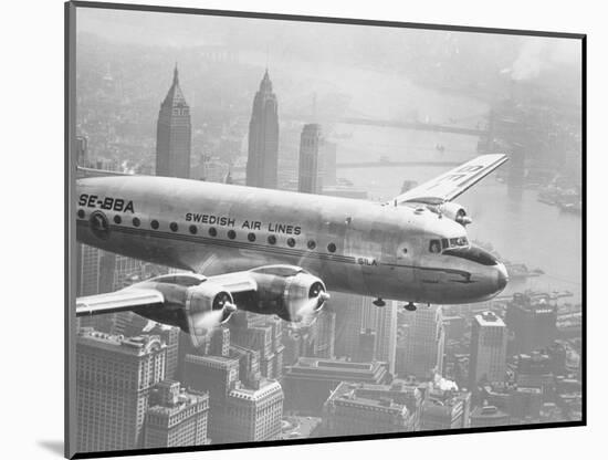 Aircraft Flying over City-null-Mounted Photographic Print