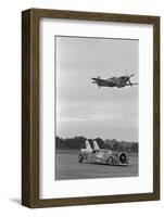 Airplane Flying over Race Car in Action-null-Framed Photographic Print