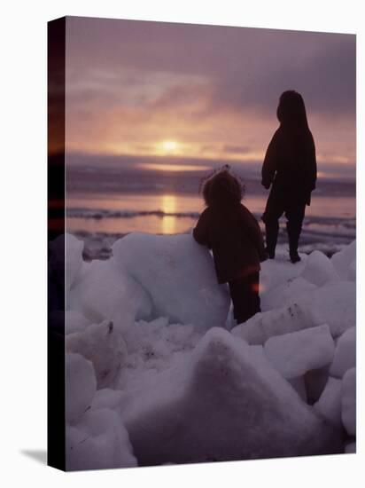 Alaska: Silhoutte of Native Alaskan Children Watching the Midnight Sun-Ralph Crane-Stretched Canvas