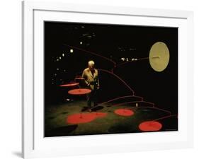 Alexander Calder Walking Past Exhibit of His Mobiles at the Guggenheim Museum-Gjon Mili-Framed Premium Photographic Print