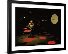 Alexander Calder Walking Past Exhibit of His Mobiles at the Guggenheim Museum-Gjon Mili-Framed Premium Photographic Print