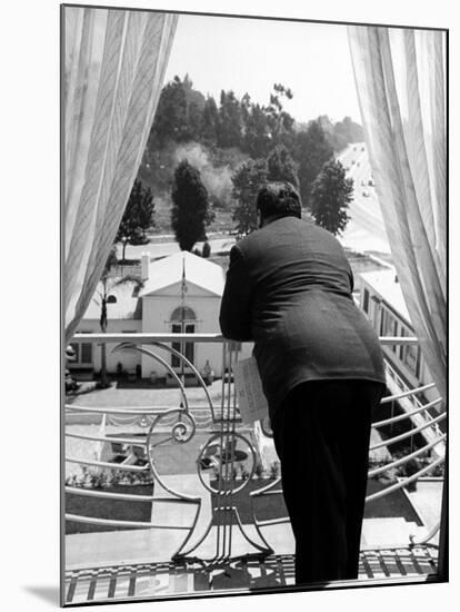 Alfred Hitchcock on Balcony Railing of Apartment, Looking Out over Grounds of Wilshire Palms-Peter Stackpole-Mounted Premium Photographic Print