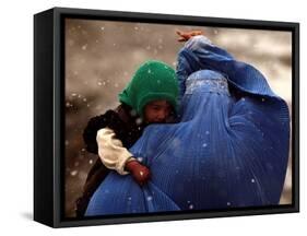 An Afghan Woman Holding Her Child Throws Back Her Burqa to See Her Way Along a Muddy Alley-null-Framed Stretched Canvas