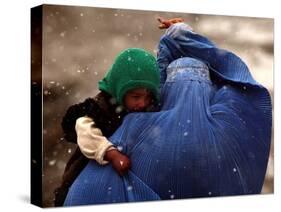 An Afghan Woman Holding Her Child Throws Back Her Burqa to See Her Way Along a Muddy Alley-null-Stretched Canvas