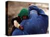 An Afghan Woman Holding Her Child Throws Back Her Burqa to See Her Way Along a Muddy Alley-null-Stretched Canvas