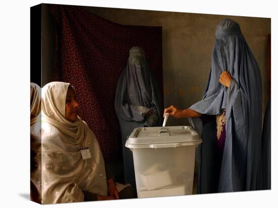 An Afghan Woman Wearing a Burqa Casts Her Ballot at a Polling Station-null-Stretched Canvas