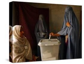 An Afghan Woman Wearing a Burqa Casts Her Ballot at a Polling Station-null-Stretched Canvas