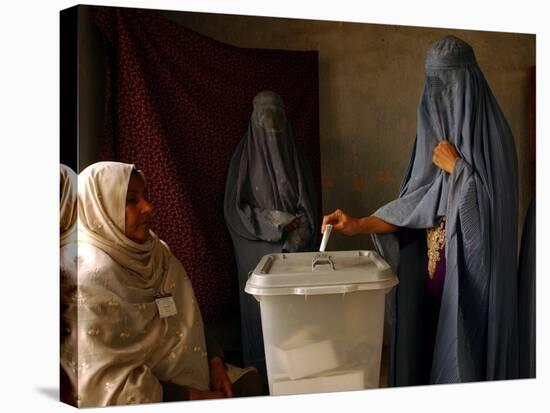 An Afghan Woman Wearing a Burqa Casts Her Ballot at a Polling Station-null-Stretched Canvas