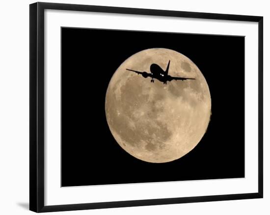 An Airliner is Silhouetted against a Full Moon-null-Framed Photographic Print