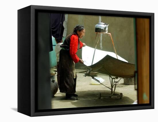 An Elderly Woman Tries to Get the Angle Right on the Blades of Solar Power Cooker to Boil Water-null-Framed Stretched Canvas