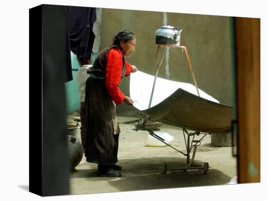 An Elderly Woman Tries to Get the Angle Right on the Blades of Solar Power Cooker to Boil Water-null-Stretched Canvas