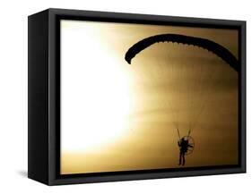 An Engine-Powered Paraglider Soars Through the Air Near Schlesen-null-Framed Stretched Canvas