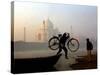 An Unidentified Cyclist Gets Down with His Cycle against the Backdrop of the Taj Mahal-null-Stretched Canvas