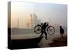 An Unidentified Cyclist Gets Down with His Cycle against the Backdrop of the Taj Mahal-null-Stretched Canvas