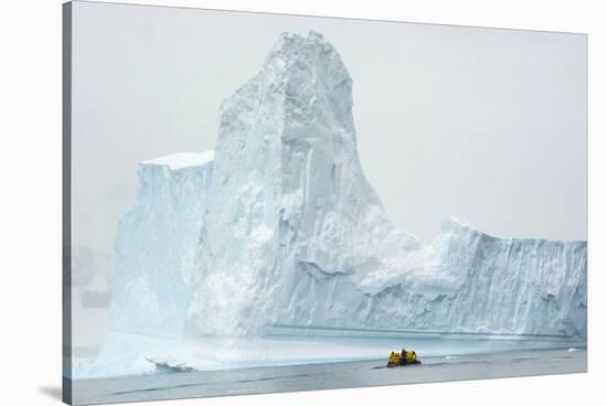 Antarctica. Charlotte Bay. Zodiac Dwarfed by a Giant Towering Iceberg-Inger Hogstrom-Stretched Canvas