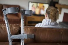 Woman Watching TV with Crutches-Anthony West-Photographic Print