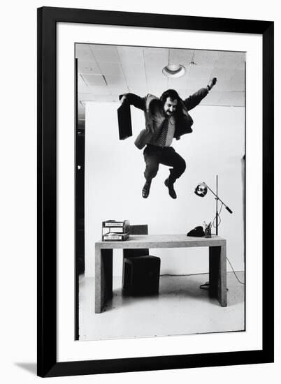 Architect and Designer Frank Gehry Jumping on a Desk in His Line of Cardboard Furniture-Ralph Morse-Framed Photographic Print