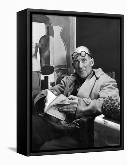 Architect Le Corbusier Sitting in Chair and Holding Book in Hands-Nina Leen-Framed Stretched Canvas