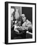 Architect Le Corbusier Sitting in Chair and Holding Book in Hands-Nina Leen-Framed Premium Photographic Print