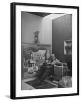 Architect Le Corbusier Sitting in Chair with Book in Hands, Glasses Perched on His Forehead-Nina Leen-Framed Premium Photographic Print