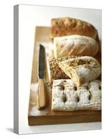 Assorted Loaves on Wooden Chopping Board-Michael Paul-Stretched Canvas