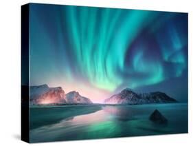 Aurora Borealis over the Sea, Snowy Mountains and City Lights at Night. Northern Lights in Lofoten-Denis Belitsky-Stretched Canvas