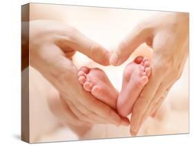 Baby Feet in Mother Hands. Tiny Newborn Baby's Feet on Female Heart Shaped Hands Closeup. Mom and H-Subbotina Anna-Stretched Canvas