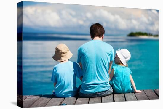 Back View of Father and Kids Sitting on Wooden Dock Looking to Ocean-BlueOrange Studio-Stretched Canvas