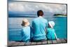 Back View of Father and Kids Sitting on Wooden Dock Looking to Ocean-BlueOrange Studio-Mounted Photographic Print
