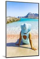 Back view of woman contemplating the sea sitting on pink sand of Falassarna beach-Roberto Moiola-Mounted Photographic Print